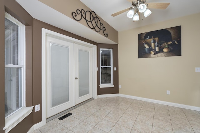 empty room featuring light tile patterned floors, visible vents, baseboards, and ceiling fan