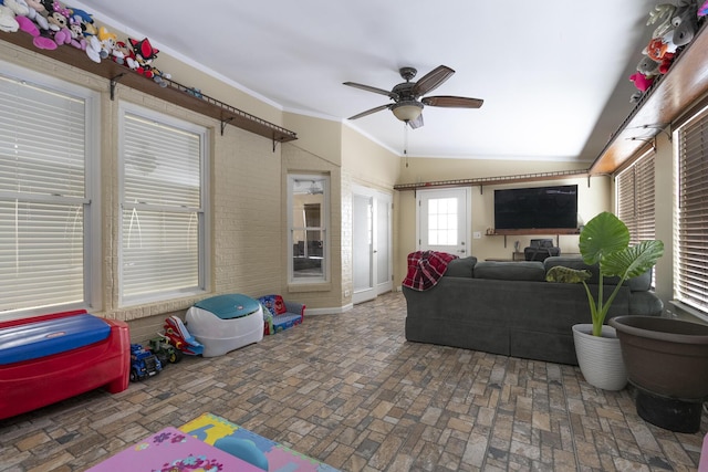 living room featuring a ceiling fan, brick floor, and ornamental molding