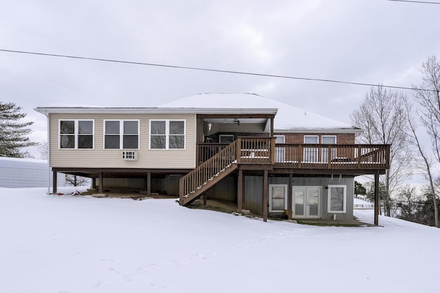 snow covered back of property with a wooden deck