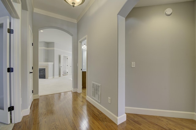 hallway with light wood-type flooring and ornamental molding