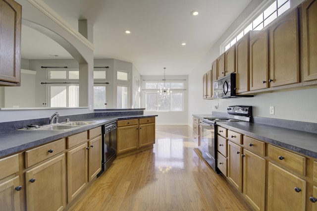 kitchen featuring an inviting chandelier, black appliances, sink, decorative light fixtures, and light hardwood / wood-style floors