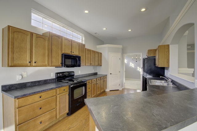 kitchen with black appliances, light wood-type flooring, and sink