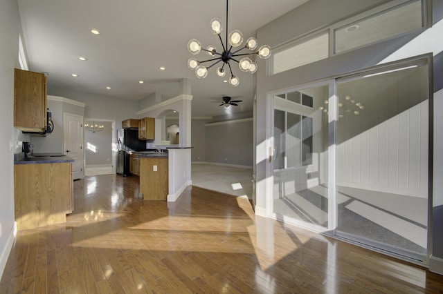 kitchen featuring pendant lighting, ceiling fan with notable chandelier, light hardwood / wood-style floors, and refrigerator