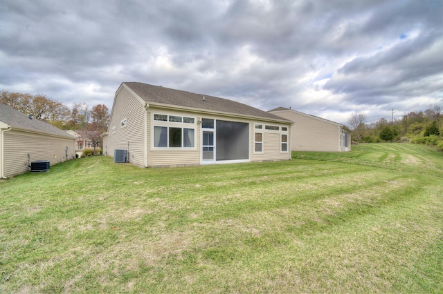 rear view of property with a lawn and central air condition unit