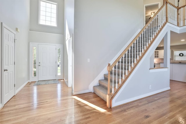 foyer entrance with a wealth of natural light, light hardwood / wood-style floors, and a high ceiling