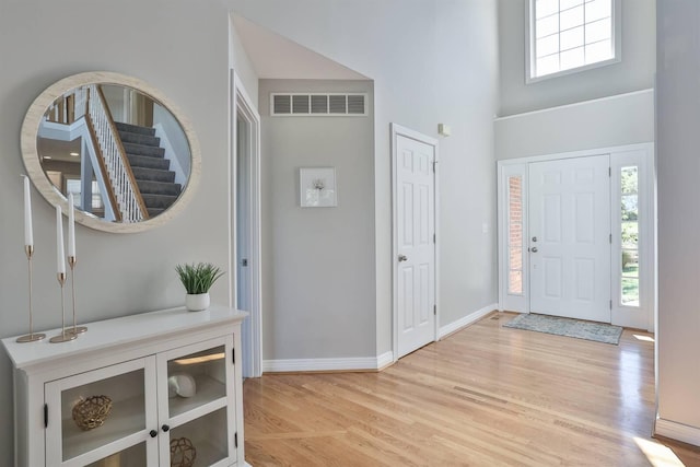 foyer entrance with a towering ceiling and light hardwood / wood-style flooring