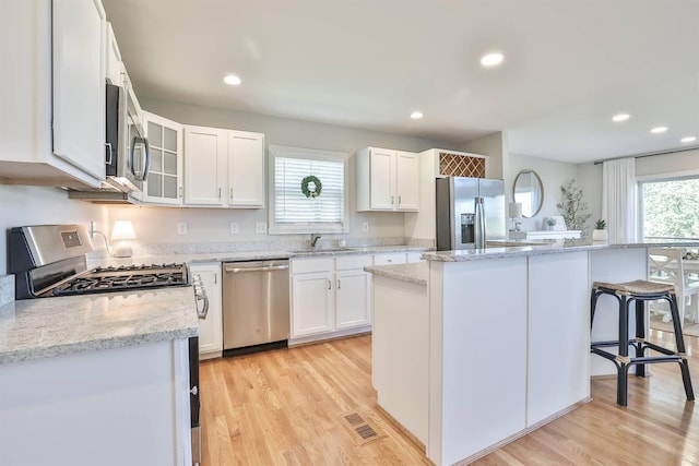 kitchen featuring a kitchen island, white cabinetry, a healthy amount of sunlight, and appliances with stainless steel finishes