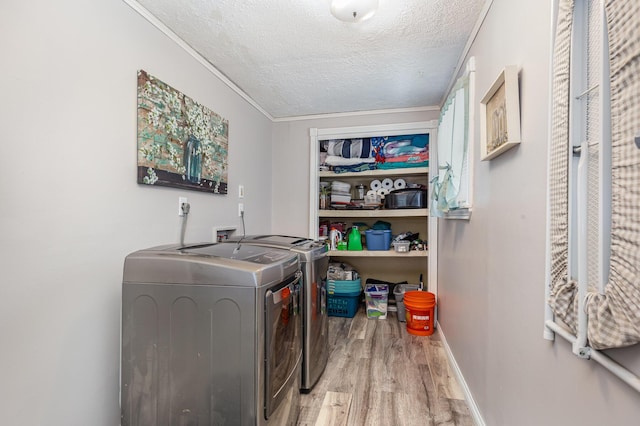 laundry room with light wood-style flooring, a textured ceiling, separate washer and dryer, laundry area, and baseboards