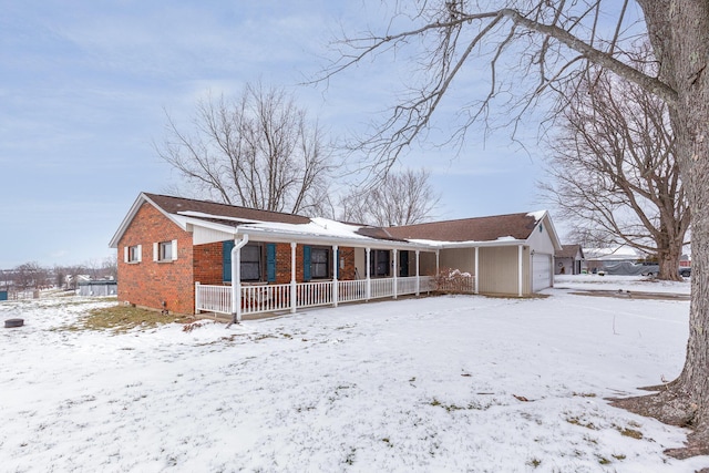 snow covered property featuring covered porch and brick siding