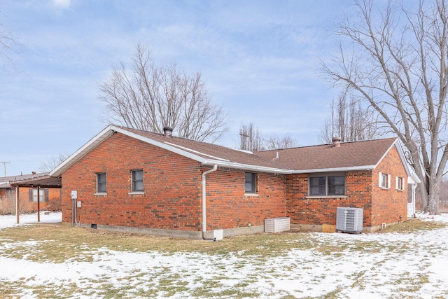 exterior space featuring brick siding, a shingled roof, and cooling unit