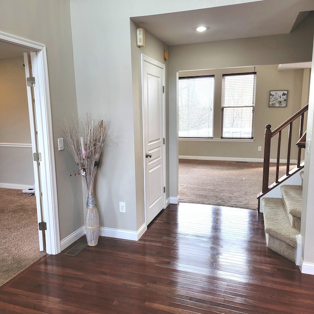 entrance foyer with stairs, carpet flooring, wood finished floors, and baseboards