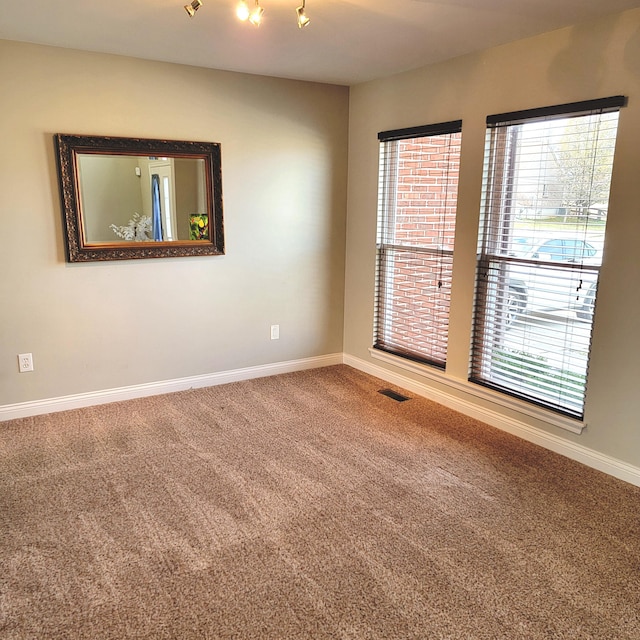 carpeted empty room featuring visible vents and baseboards