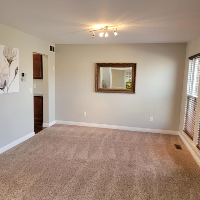 carpeted empty room featuring visible vents and baseboards