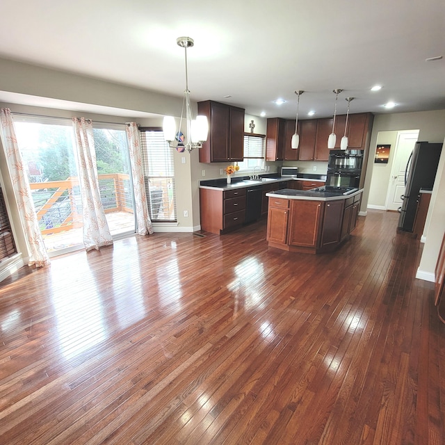 kitchen featuring black dishwasher, baseboards, a kitchen island, dark wood-type flooring, and freestanding refrigerator