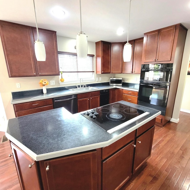 kitchen featuring black appliances, wood finished floors, a sink, and decorative light fixtures