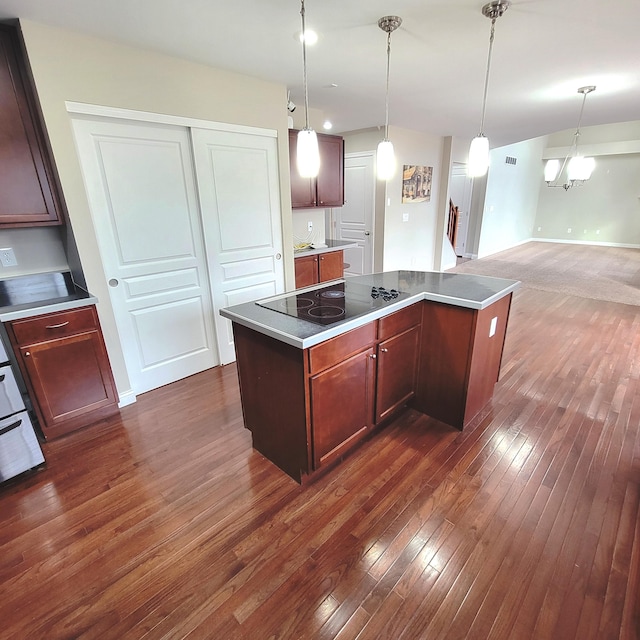 kitchen featuring hanging light fixtures, black electric stovetop, dark wood finished floors, and a center island