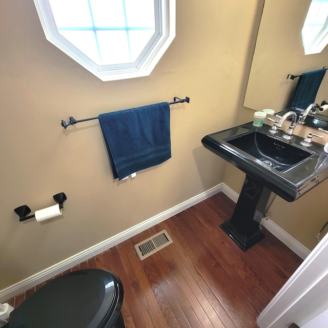 bathroom featuring toilet, wood finished floors, visible vents, and baseboards