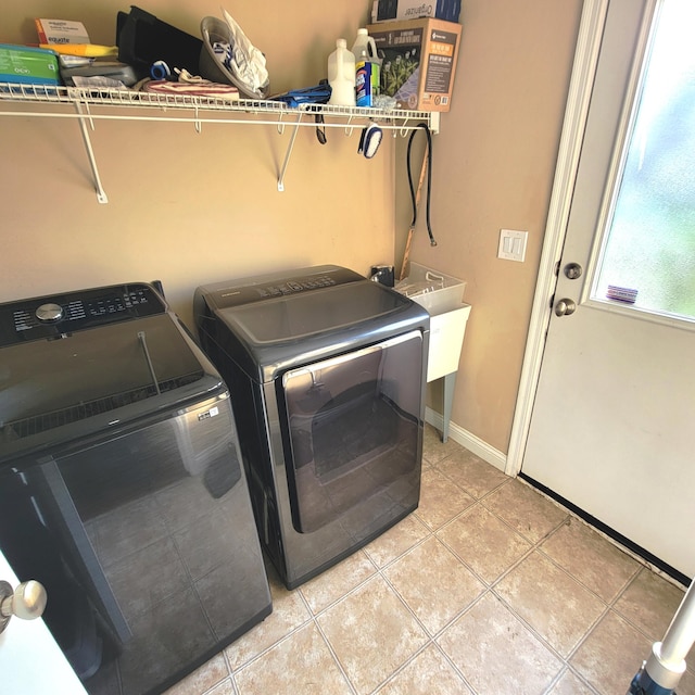 laundry area featuring washing machine and dryer, laundry area, baseboards, and light tile patterned floors