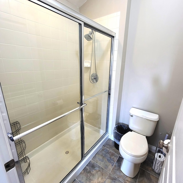 bathroom with a stall shower, baseboards, and toilet