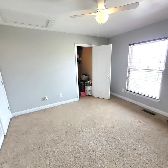 unfurnished bedroom with carpet, visible vents, attic access, ceiling fan, and baseboards