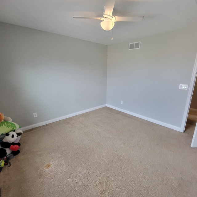 carpeted empty room with baseboards, visible vents, and ceiling fan