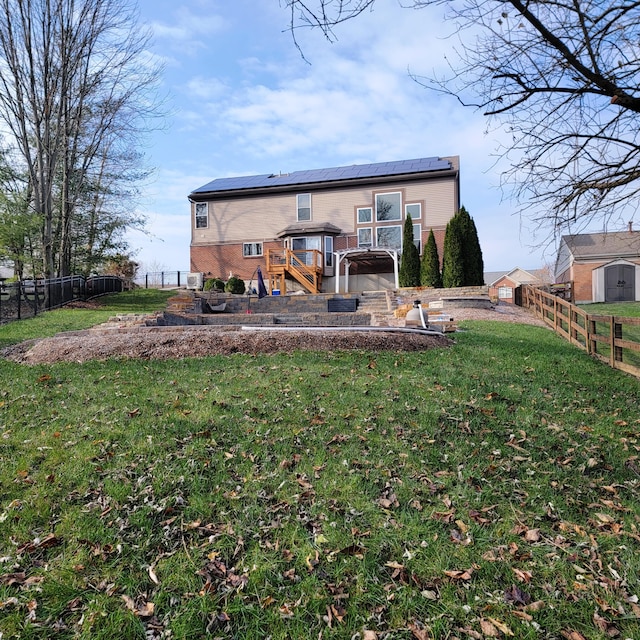 rear view of house featuring roof mounted solar panels, brick siding, a yard, and a shed