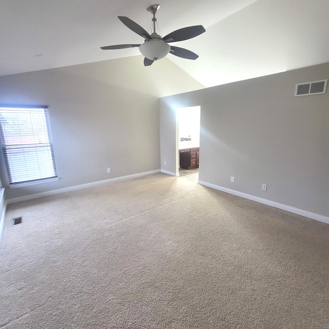 unfurnished room featuring ceiling fan, light colored carpet, visible vents, baseboards, and vaulted ceiling