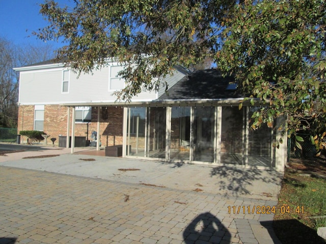 back of property with a sunroom and a patio