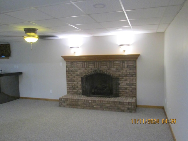 unfurnished living room with carpet flooring, a paneled ceiling, and a brick fireplace