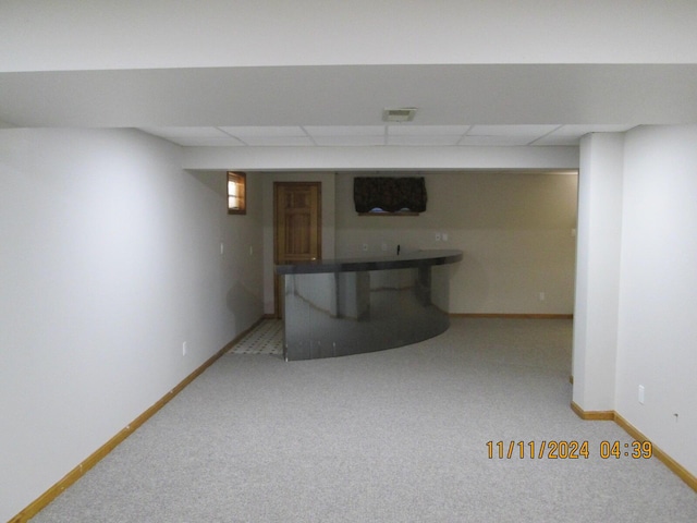 basement featuring a drop ceiling and light carpet