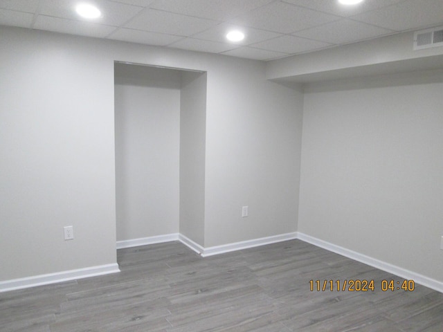 basement featuring a paneled ceiling and wood-type flooring