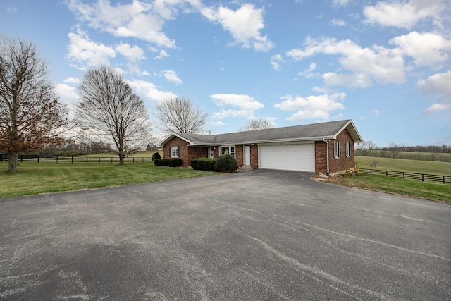 single story home with a rural view, a front yard, and a garage