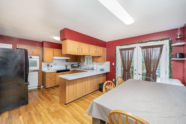 kitchen with french doors, black appliances, light wood-type flooring, tasteful backsplash, and kitchen peninsula