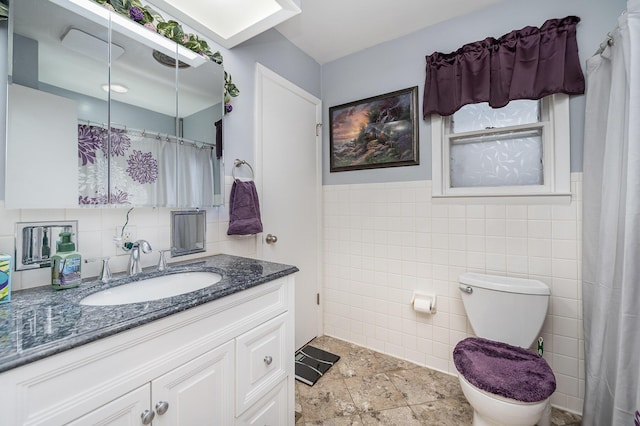 bathroom featuring tile patterned floors, vanity, toilet, and tile walls