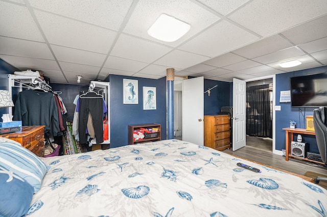 bedroom with a closet, wood-type flooring, and a drop ceiling