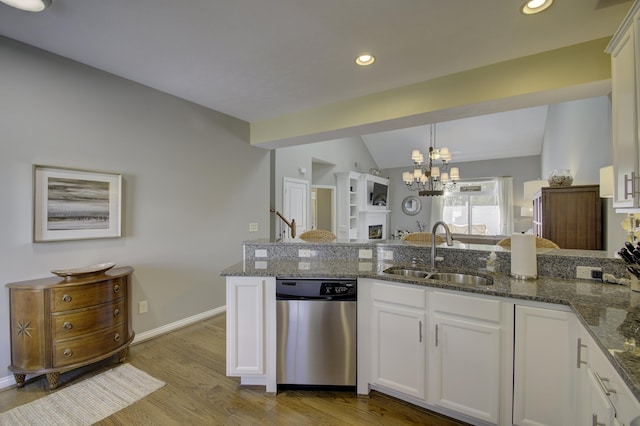 kitchen featuring stainless steel dishwasher, dark stone counters, sink, white cabinets, and lofted ceiling