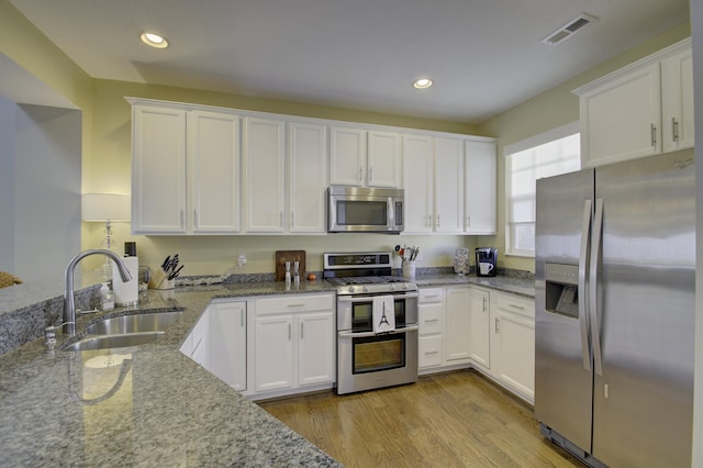 kitchen featuring white cabinetry, sink, light stone counters, and appliances with stainless steel finishes