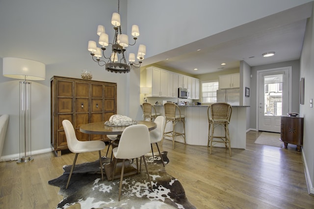 dining room with light wood-type flooring and a notable chandelier