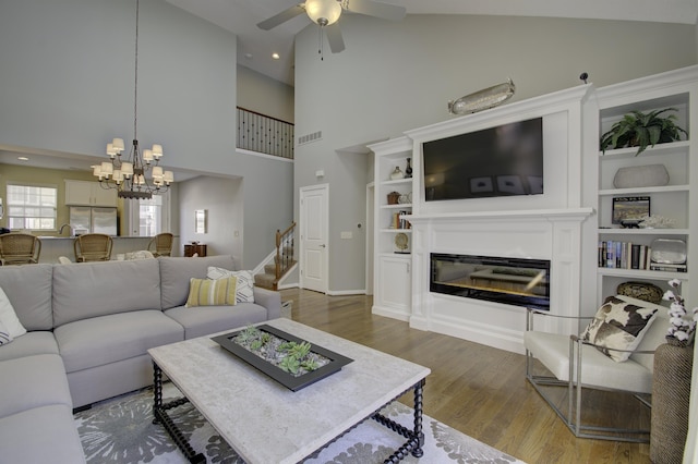 living room with ceiling fan with notable chandelier, dark hardwood / wood-style floors, and high vaulted ceiling