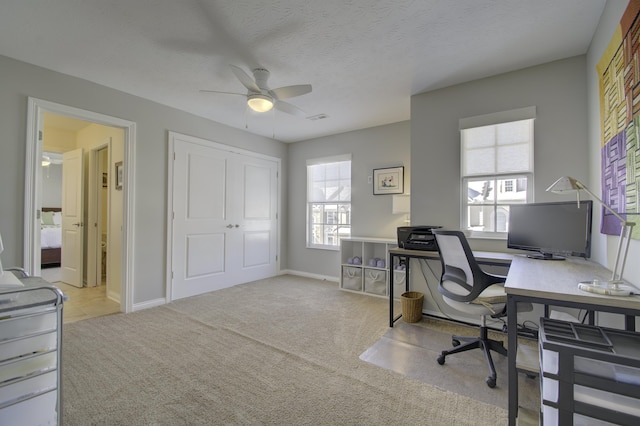 office space featuring a textured ceiling, light colored carpet, and ceiling fan