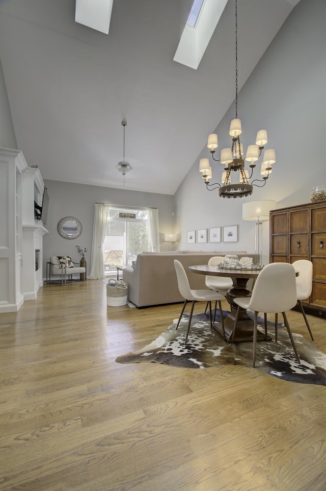 dining area featuring a skylight, hardwood / wood-style floors, high vaulted ceiling, and a notable chandelier