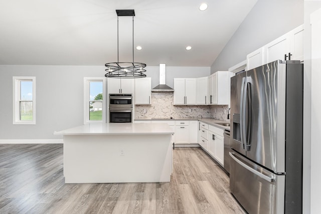 kitchen with wall chimney exhaust hood, a kitchen island, pendant lighting, white cabinets, and appliances with stainless steel finishes