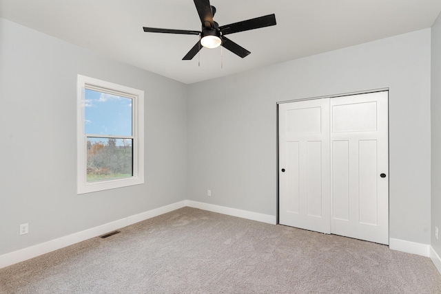 unfurnished bedroom featuring light carpet, a closet, and ceiling fan