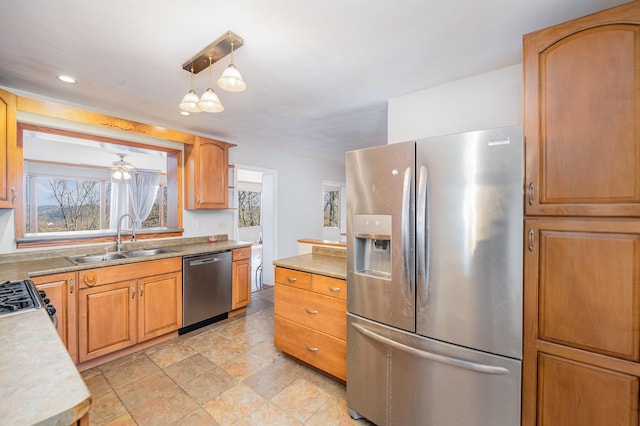 kitchen with appliances with stainless steel finishes, ceiling fan, hanging light fixtures, and sink