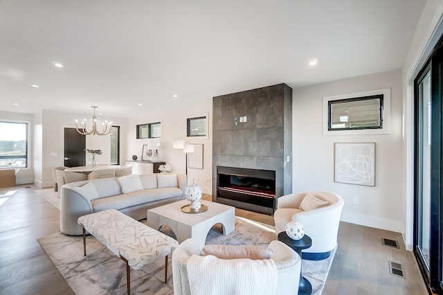 living room with a tile fireplace, a chandelier, and light hardwood / wood-style floors