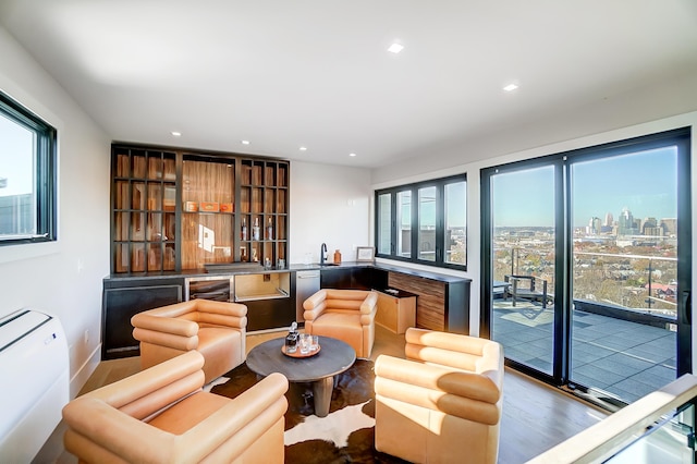 living room with hardwood / wood-style flooring, a healthy amount of sunlight, indoor wet bar, and wine cooler