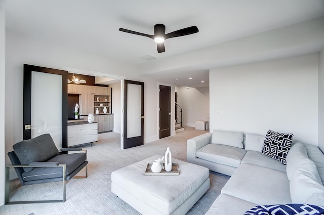 carpeted living room with french doors and ceiling fan with notable chandelier