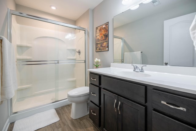 bathroom with walk in shower, hardwood / wood-style floors, vanity, and toilet