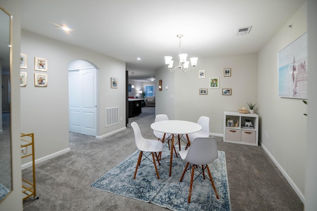 dining space with dark carpet and an inviting chandelier