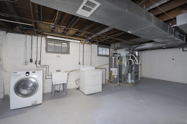 basement featuring heating unit, sink, gas water heater, and independent washer and dryer